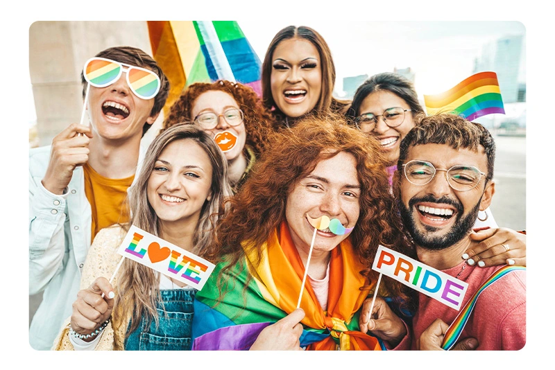 a group of people hold pride slogan and wave a rainbow flag to celebrate pride month